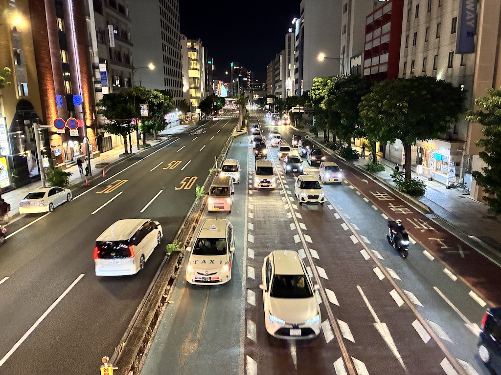 오키나와 나하 시내 야간 도로 — 50km/h 속도 제한이 노면에 표시된 4차선 도로와 차량들