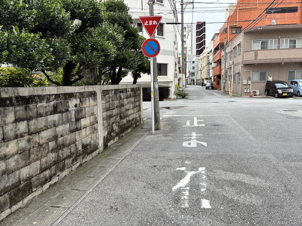 오키나와 골목길 입구의 빨간 역삼각형 止まれ(토마레) 일시정지 표지판과 노면의 止まれ 흰색 글자