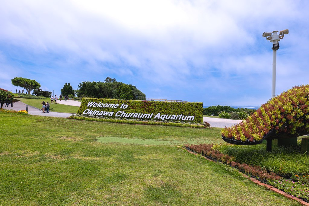 오키나와 해양박공원 입구의 Welcome to Okinawa Churaumi Aquarium 초록 화단 간판
